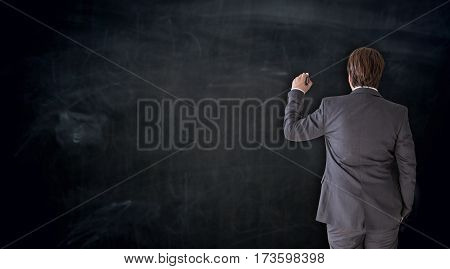 Businessman writing with chalk on blackboard concept picture
