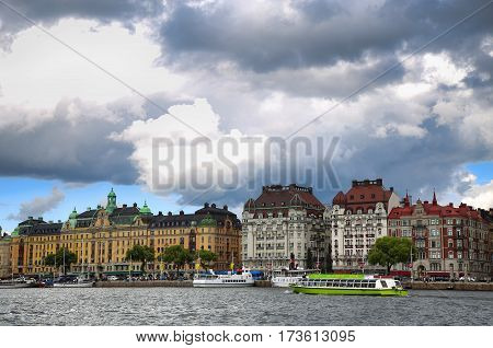 STOCKHOLM SWEDEN - AUGUST 20 2016: Many people walk and visit on Strandvagen street on Ostermalm distric with touristic sightseeing boats in Stockholm Sweden on August 20 2016.