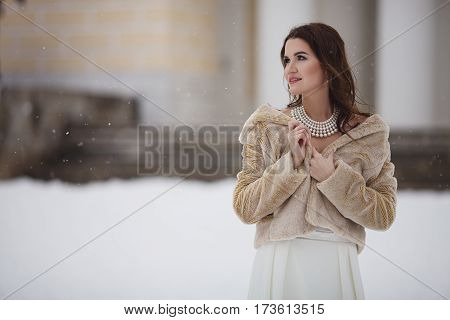 Young girl in a fur coat on eco background old building
