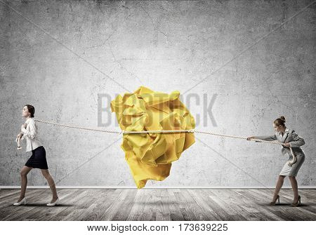 Two businesswomen playing tag of war game