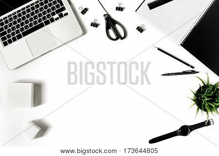 White office desk frame with laptop keyboard and supplies. Laptop, notebook, pen, clips, pencil, plant, scissors and office supplies on white background. Flat lay, top view, mockup