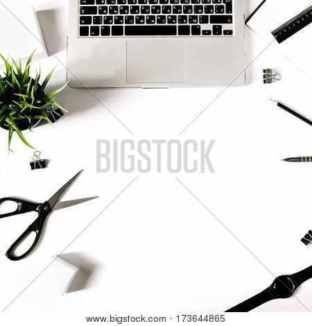 White office desk frame with laptop keyboard and supplies. Laptop, notebook, pen, clips, pencil, plant, scissors, watch and office supplies on white background. Flat lay, top view, mockup