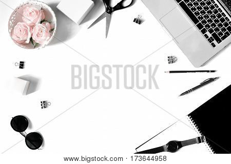 White office desk frame with laptop keyboard and supplies. Laptop, notebook, pen, roses, sunglasses, clips, pencil, plant, scissors, watch and office supplies on white background. Flat lay, top view, mockup