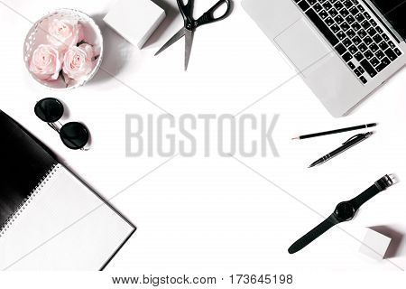 White office desk frame with laptop keyboard and supplies. Laptop, notebook, pen, roses, sunglasses, pencil, scissors, watch and office supplies on white background. Flat lay, top view, mockup