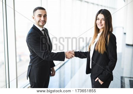 Businessman and Businesswoman handshake in office with big panoramic windows