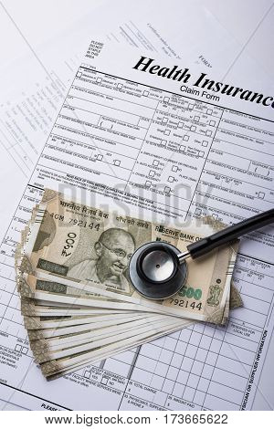 Health insurance form with indian money or currency notes of 500 and 2000 rupees and stethoscope concept for life planning