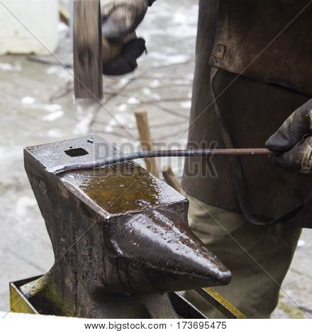 Detail shot of hammer forging hot iron at anvil.