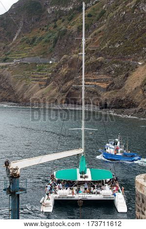 PORTO MONIZ MADEIRA PORTUGAL - SEPTEMBER 5 2016: Catamaran while sailing with tourists docked in Porto Moniz. Madeira Porttugal