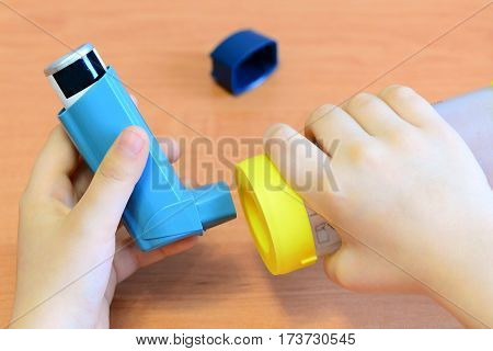 Child patient holds asthma inhaler and spacer in hands. Medical asthma spacer and aerosol inhaler spray for treatment and management bronchial asthma allergy. Inhaled steroids. Child breathing problem