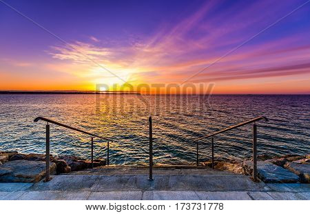 Steps on a beach with sunset on the ocean sea. Landscape photo of sunrise or sunset on a natural beach in Piran Slovenia.