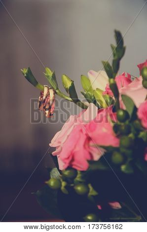 Gold wedding rings are beautiful hanging on a branch wedding bouquet with pink roses