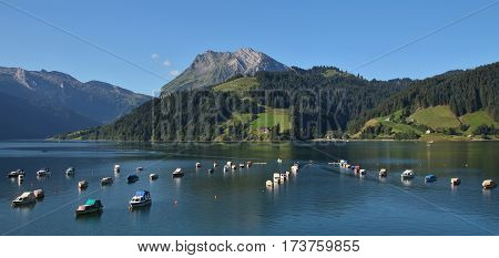 Summer morning at lake Wagital. Fishing boats and mount Fluebrig.