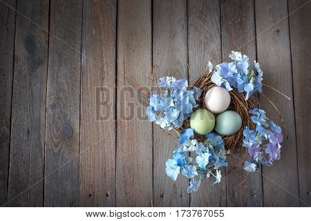 Easter eggs in a nest with blue hydrangeas on dark wood