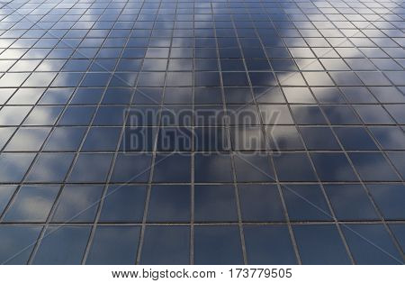 pattern of square black glossy ceramic tiles with reflecion of sky and clouds
