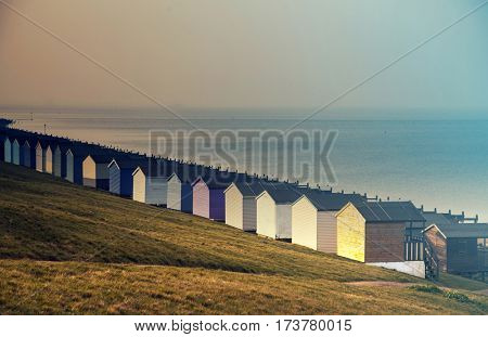Row of colored beach huts with stormy blue sky on the beach of Tankerton near Whitstable in Kent, UK