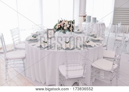 Well decorated guest numbered table in tenderless wedding hall, which is in white and silver colours