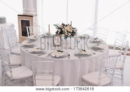 Well decorated guest numbered table in tenderless wedding hall, which is in white and silver colours