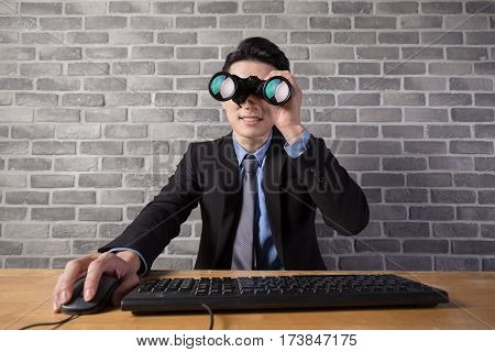 business man use binocular with brick wall in officeasian