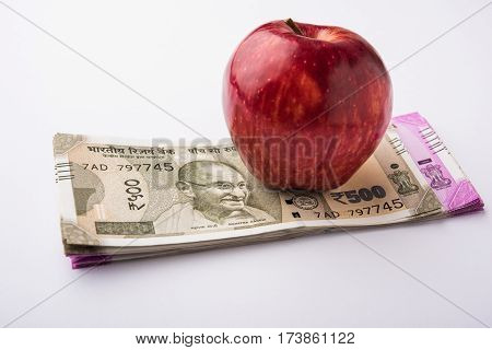 indian new currency notes of 500 and 200 rupees with fresh red apple and stethoscope - India and healthcare concept