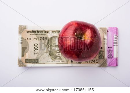 indian new currency notes of 500 and 200 rupees with fresh red apple and stethoscope - India and healthcare concept