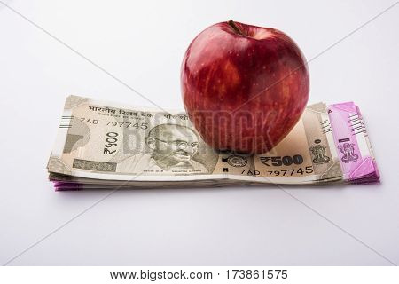 indian new currency notes of 500 and 200 rupees with fresh red apple and stethoscope - India and healthcare concept