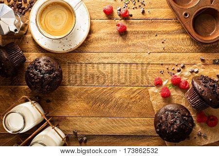 Double chocolate muffins with raspberry and a cup of coffee in a rustic setting overhead shot