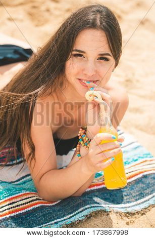 Beach woman drinking cold drink beverage having fun at beach party. Female babe in bikini enjoying orange water from glass boutle. summer concept
