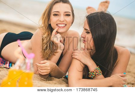 Gierlfriends drinking cold drink beverage having fun at beach party. Female babes in bikini enjoying orange water from glass boutle. summer concept