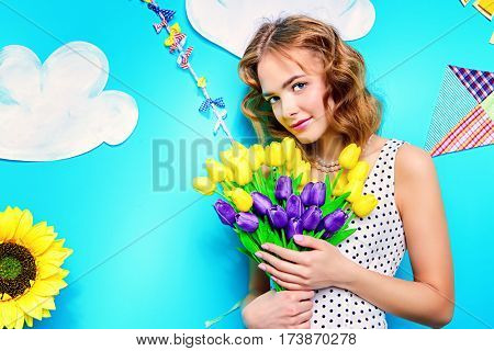 Pretty young woman with beautiful foxy hair holds a bouquet of tulips. Spring and summer holidays. Women's Day. Beauty, fashion concept.