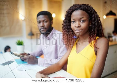 Young manager looking at camera on background of co-worker