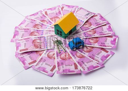 indian real estate or residential model house with new currency notes, keys, toy car and calculator, selective focus