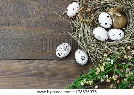 Top view easter background.Happy easter eggs pained also rabbit and cross on nest.Texture rustic wooden with decorations flowers and copy space.