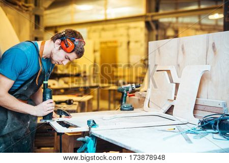 Professional cabinetmaker grinding wooden workpiece