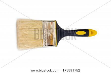 Flat paint brush with width of the head 75 mm and with a rubberised black and yellow handle on a light background
