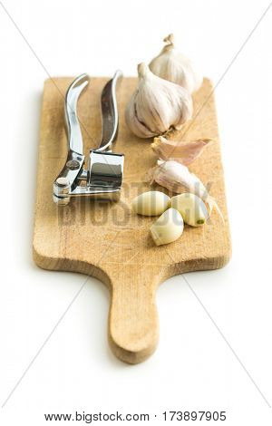 Garlic and garlic press on cutting board isolated on white background.