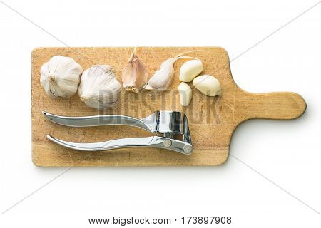 Garlic and garlic press on cutting board isolated on white background.