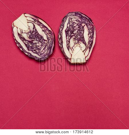 The fresh red cabbage cut in half on a red background