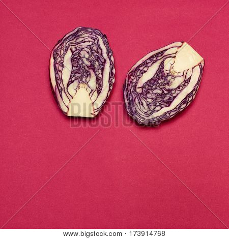 The fresh red cabbage cut in half on a red background