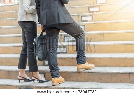 Businessman and Business woman walking up stairs with bags to office.