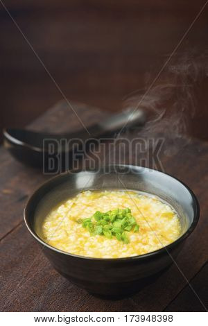 Asian congee bowl on rustic wooden table background.