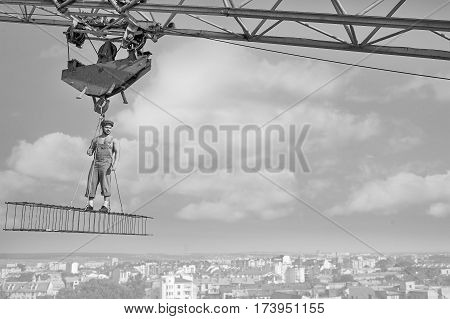 Working high. Muscular confident retro builder standing on a crossbar hanging high above the city copyspace profession fearlessness heights peaceful confident successful development city concept