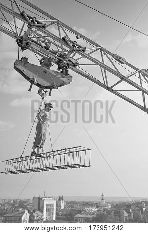Retro professional. Vertical monochrome shot of a professional builder dressed vintage styled standing on crossbar hooked to construction crane at the site profession job occupation building industry