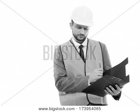 Successful developer. Monochrome studio shot of a serious businessman architect wearing protective helmet and safety west writing on his clipboard copyspace professionalism development concept