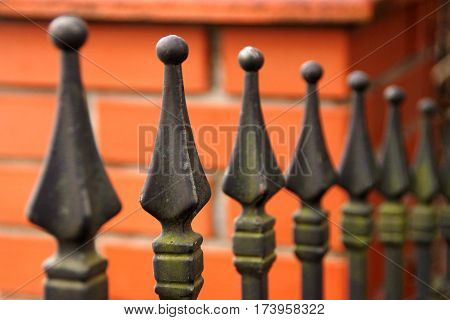 Metal heads residential fence on bricks, background image