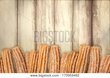 Churros arranged in row on wooden background