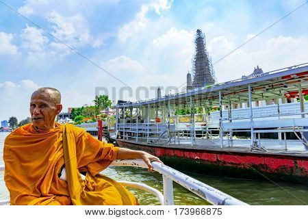 BANGKOK THAILAND - JANUARY 30: Thai buddhist monk on a boat on the Chao Phraya river with Wat Arun Temple in the background January 30 2017 in Bangkok
