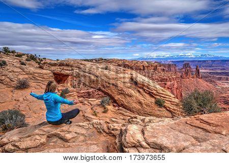 Young woman meditating at cliff by Mesa Arch. Canyonlands National Park. Moab. Utah. United States.