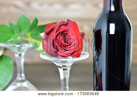 Red rose two wine glasses and bottle of red wine on wooden background