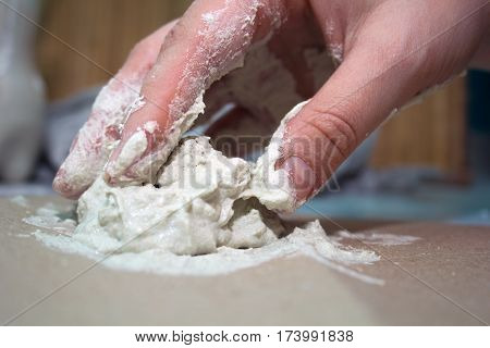 close up hands of ceramist with white clay