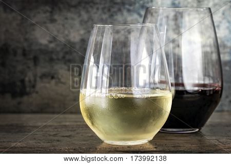White and red wine in modern stemless glasses, with slate and timber background with copy space.